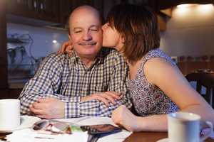 A young woman embraces her father at the kitchen table