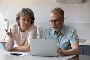 Older couple with a laptop and calculator, discussing their finances