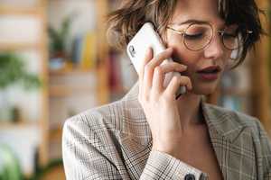 Serious young businesswoman using mobile phone