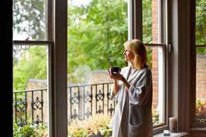Middle aged women enjoying a cup of coffee looking out to her garden