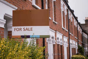 Red brick terraced houses with a 'for sale' sign