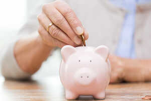 An older woman saving coins in a piggy bank