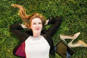 Young female employee relaxing on the grass in a park