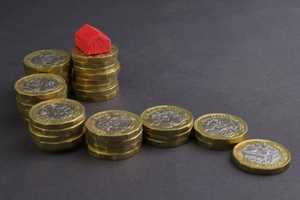 An ascending pile of one pound coins topped by a red model of a house